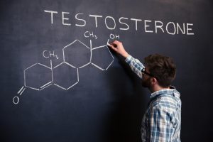A man writes "testosterone" on a blackboard