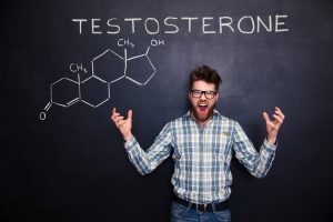 A man triumphantly yells, having successfully written "testosterone" on blackboard
