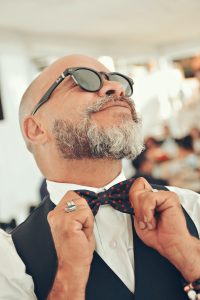 A man happily adjusts his bow-tie, which sits in the approximate location of his thyroid