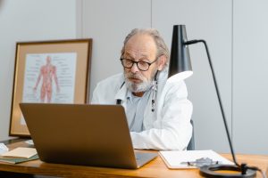 A doctor looks at a laptop